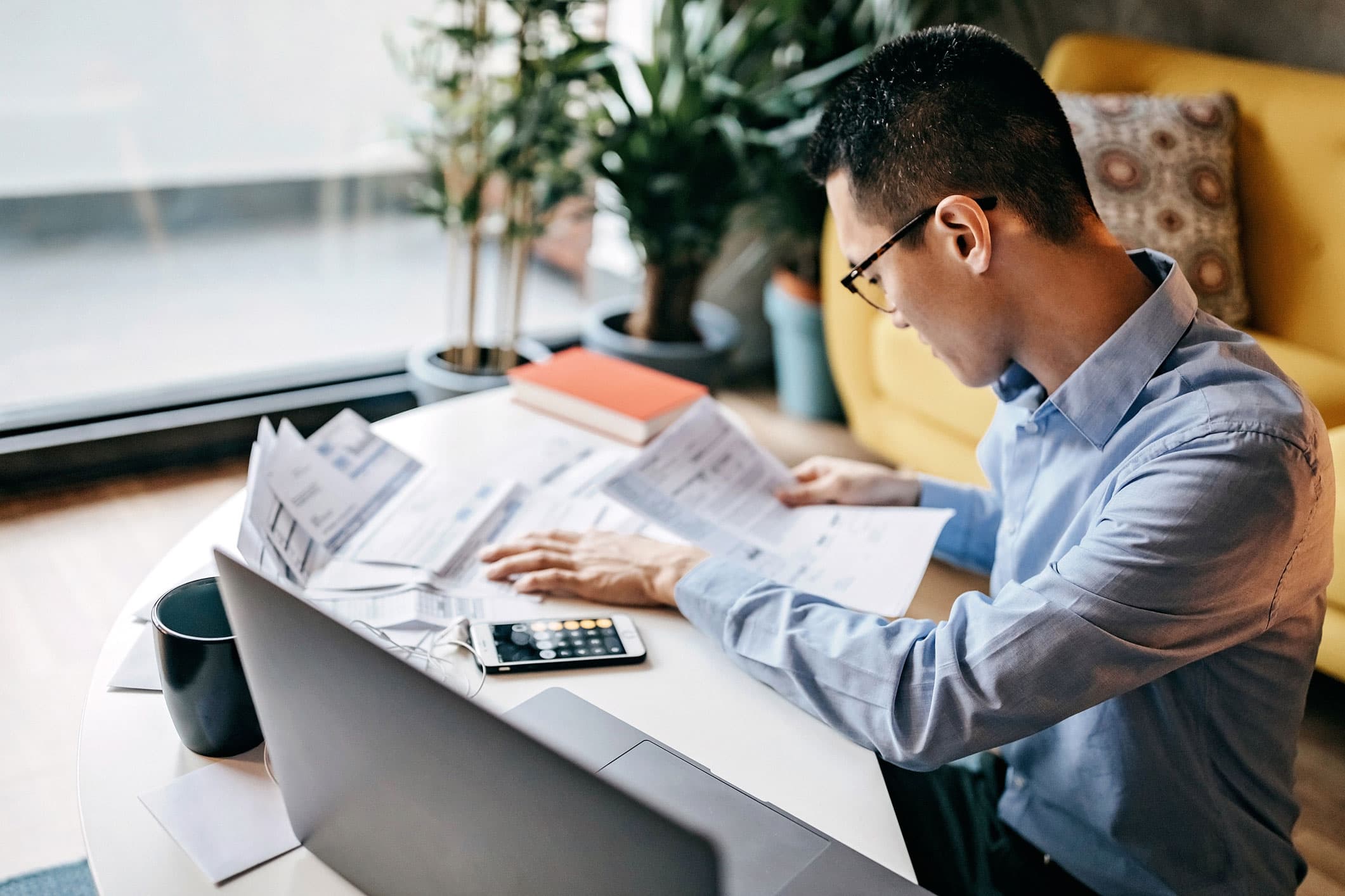 Real estate investor reviewing mortgage paperwork with a calculator at a desk